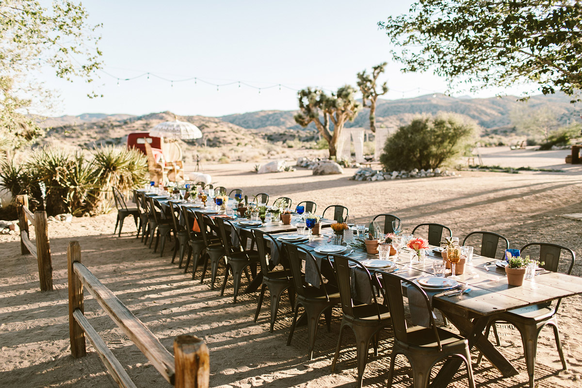 A modern outdoor event table setting in the desert. Joshua trees are in the background